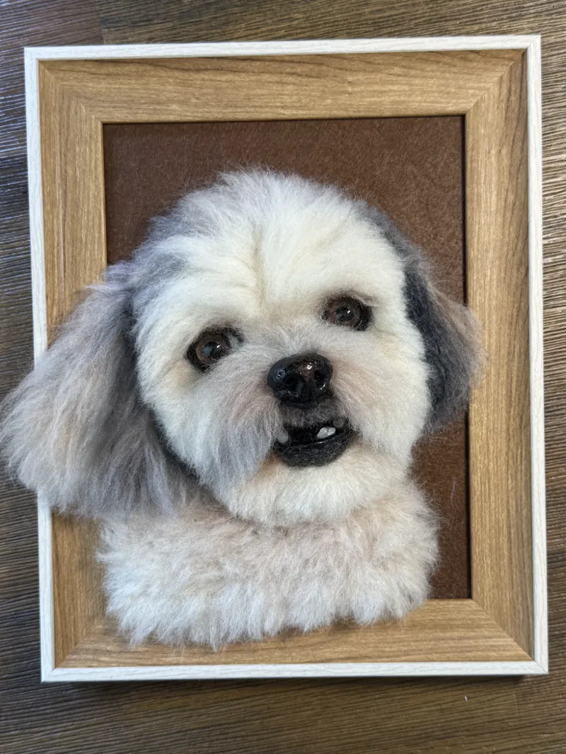 Framed needle felted portrait of a black and tan dachshund beside the reference photo